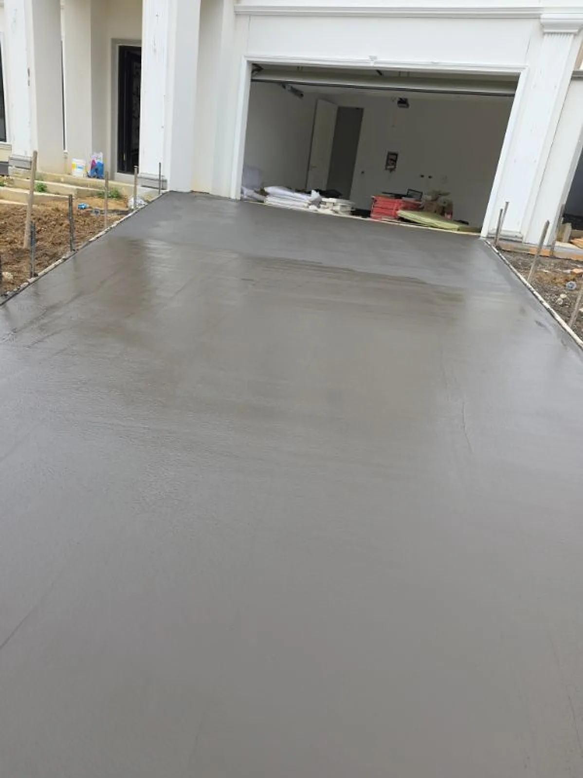 Freshly poured driveway outside a double garage