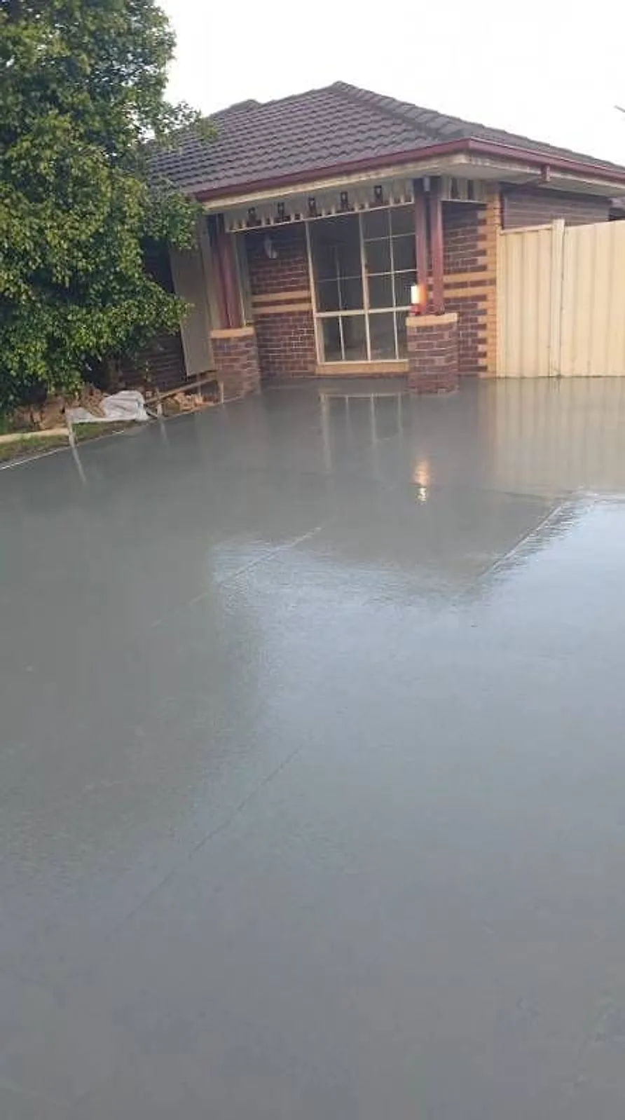Freshly poured slab in front of a brick home